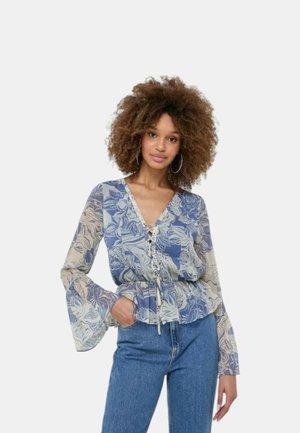 Blusa floreale fluida blu e beige con maniche a campana lunghe, scollo a V e dettaglio con fiocco frontale, realizzata in tessuto leggero con una texture liscia.