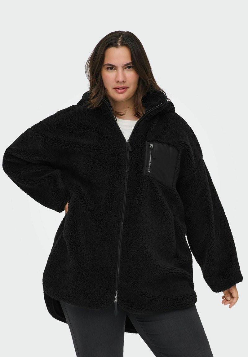 Melna polāra jaka ar kapuci, pārāk liels izmērs, teksturēta virsma, pilns zippers un neliela kabata ar zippers uz krūts. Mīksts un silts materiāls.