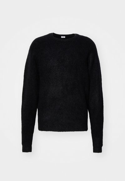 Suéter negro de cuello redondo hecho de un material suave y texturizado. Presenta mangas largas y un corte relajado sin adornos visibles.
