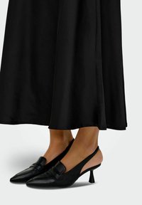 Črne slingback petke z ovalnim prstom, teksturiranim usnjem, širokim trakom čez sprednji del in zoženim srednje visokim petam.