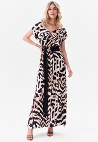 Robe maxi avec un imprimé zèbre en noir et beige. Encolure en V, manches courtes flottantes, taille cintrée avec une ceinture noire.