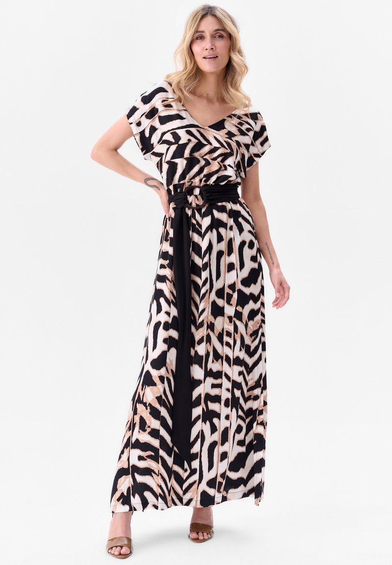 Robe maxi avec un imprimé zèbre en noir et beige. Encolure en V, manches courtes flottantes, taille cintrée avec une ceinture noire.