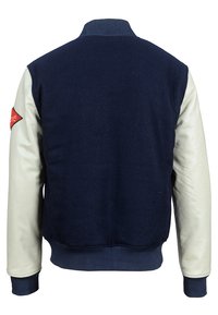 Giacca in lana blu navy con maniche in pelle crema, colletto e polsini a coste, e una toppa ricamata rossa sulla manica sinistra.