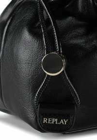 Zwarte leren tas met textuur, hoek met glanzende ronde metalen knop en de merknaam "REPLAY" in reliëf op de gestikte label.