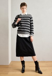 Pulover cu dungi gri și negre, cămașă albă cu guler, fustă neagră și botine negre lucioase. Texturi elegante și linii ascuțite.