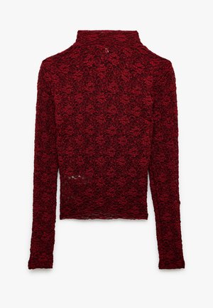 Maglia rossa a maniche lunghe con collo alto, realizzata in un tessuto di pizzo testurizzato con motivo floreale. Design aderente con orlo curvo.