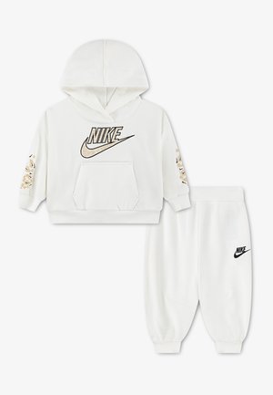 Biała dziecięca bluza z kapturem Nike z logo w panterkę i dopasowane białe spodnie dresowe z czarnym logo Nike.