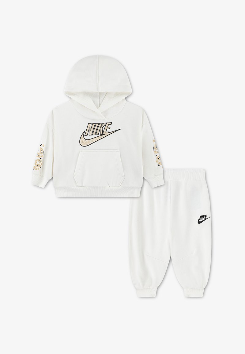 Бяла детска блуза с качулка Nike с лого с леопардов принт и бели спортни панталони с черно лого Nike.