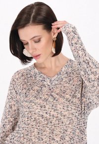 Sweter dzianinowy z dekoltem w kształcie litery V, z teksturowanym wzorem w odcieniach beżu, różu i fioletu. Długie rękawy z ozdobnymi mankietami.