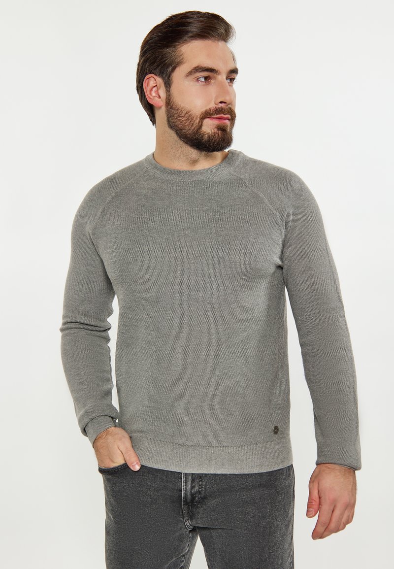 Pulover gri tricotat cu un finisaj texturat, decolteu rotund și manșoane lungi tip raglan. Prezintă un accent subtil cu logo la tiv.