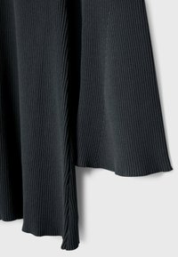 Tejido acanalado de color gris oscuro, que presenta una superficie texturizada y un diseño fluido con una ligera abertura en el borde inferior.