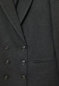 Blazer grigio scuro con tessuto testurizzato, design doppiopetto, sei bottoni neri lucidi e una tasca sul petto con dettagli a piping.
