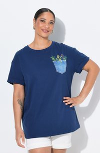 Tmavě modré tričko s ohrnutými rukávy, s denimovou kapsou zdobenou vyšívanými květinami. Měkká bavlněná textura, volný střih.