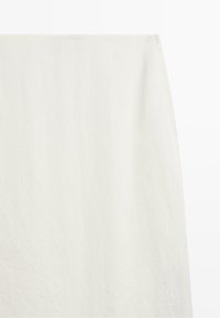 Off-white rechte rok met een subtiele textuur en een kleine rits aan de bovenste rechterkant.