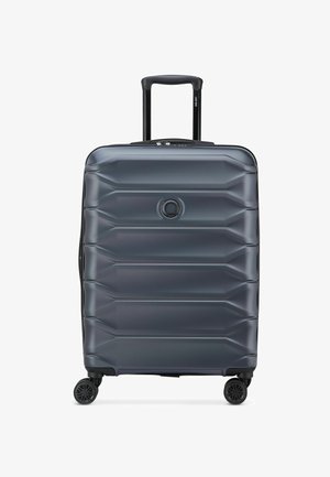 Valise rigide gris foncé avec quatre roues et une poignée télescopique, vue de face sur fond blanc.