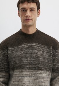 Gestrickter Pullover in dunkelbraunen und grauen Tönen mit horizontalem Streifenmuster. Verfügt über einen runden Ausschnitt und eine weiche, flauschige Textur.