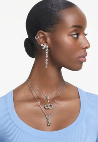 Silver smycken innehåller hängande örhängen med geometriska former och ett karaktärsbetonat inslag, tillsammans med lager av halsband i olika längder och designer.