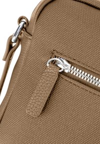 Braune strukturierte Schultertasche mit einem silbernen Reißverschluss und einem dekorativen Reißverschlussanhänger. Das Material hat ein gewebtes Muster. Kompaktes Design.