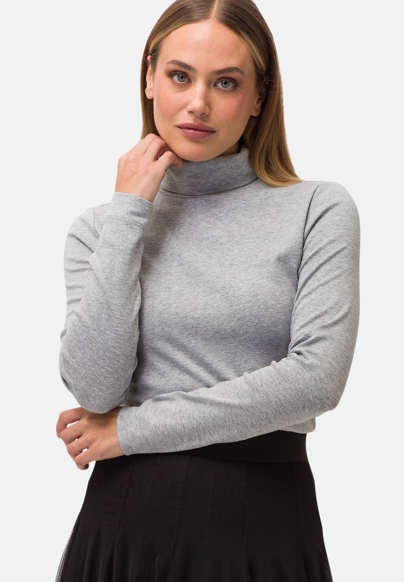Grauer Rollkragenpullover aus glattem Strickstoff, mit langen Ärmeln und tailliertem Design, kombiniert mit einem schwarzen Rock an der Taille.