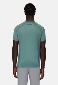 Short-sleeve, light green athletic shirt with flatlock seams and logo at the back. Smooth texture, fitted design, and moisture-wicking fabric.