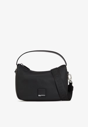 Bolsa de ombro em couro preto com fecho de correr no topo, textura suave, forma esguia e alça ajustável com detalhes do logótipo. Patch da marca quadrado visível.