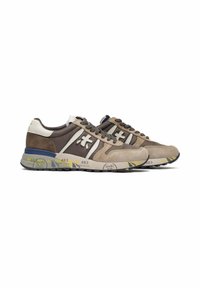 Pair of brown and beige sneakers with white and yellow accents, logo on sides, laces, and printed details on midsole.