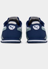 Σκούρα μπλε αθλητικά παπούτσια με επενδεδυμένο γιακά, λευκές λεπτομέρειες και υφασμάτινες υφές με ανάγλυφα σχέδια. Διαθέτουν έναν κυκλικό λογότυπο στη φτέρνα. Λαστιχένια σόλα.