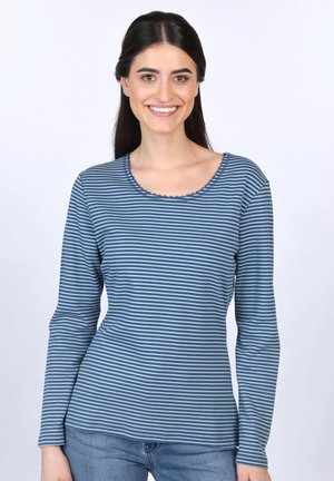 Langärmliges gestreiftes Hemd in Blautönen mit einem wellenförmigen Ausschnitt und einer weichen Textur, kombiniert mit einer hellen Jeans.