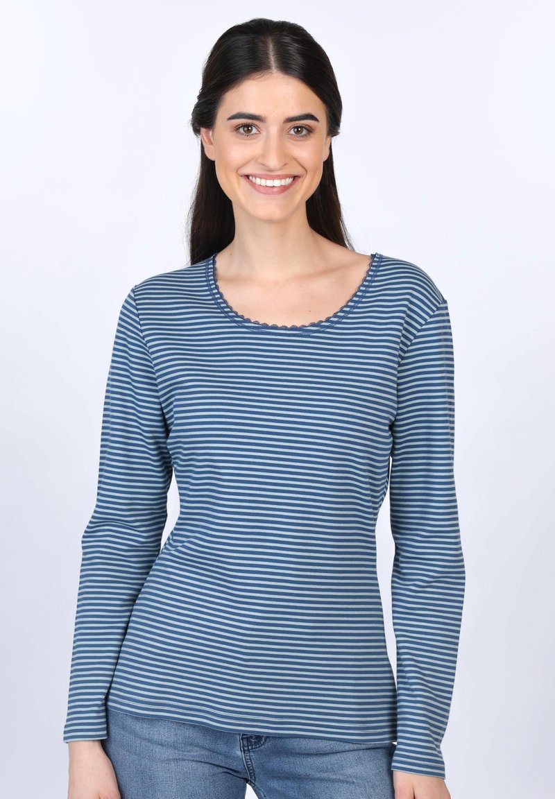 Langärmliges gestreiftes Hemd in Blautönen mit einem wellenförmigen Ausschnitt und einer weichen Textur, kombiniert mit einer hellen Jeans.