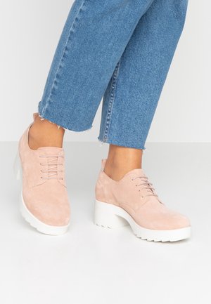 Roze suède schoenen met een ronde neus, vetersluiting en chunky witte plateauhak, gecombineerd met cropped denim broeken.