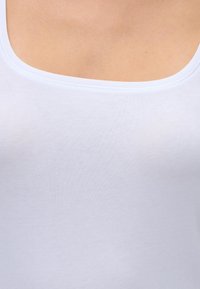 Balts kokvilnas bez piedurknēm tops ar apaļu kakla izgriezumu, gluda tekstūra un bez redzamām rakstām vai rotājumiem. Audums izskatās mīksts un viegls.