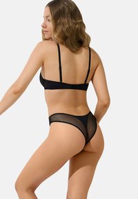 Ensemble de lingerie noire avec un dos en maille transparente et des bretelles. Le soutien-gorge a des bretelles ajustables, tandis que les culottes offrent une couverture minimale et une coupe moderne.