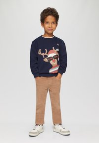 Marine sweatshirt met een rendier grafiek en tekst, gecombineerd met beige corduroy broek en witte sneakers. Casual outfit voor kinderen.