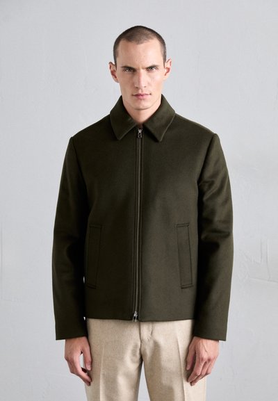 Chaqueta de mezcla de lana en color verde oliva con solapa, cierre frontal de cremallera y dos bolsillos laterales. Presenta una forma estructurada y una textura suave.