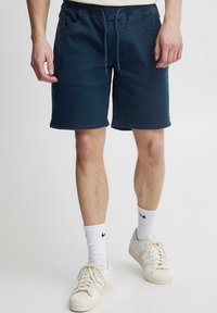 Pantalones cortos azul marino hechos de tela suave, con cintura elástica, cordón y dos bolsillos frontales. Sin patrones ni detalles visibles.