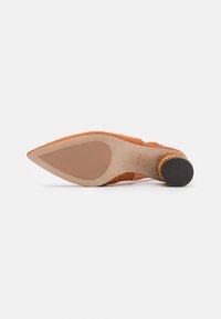 Zapato de tacón alto de ante naranja con punta afilada, suela beige lisa y un acento texturizado en el tacón. Apto para ocasiones formales.