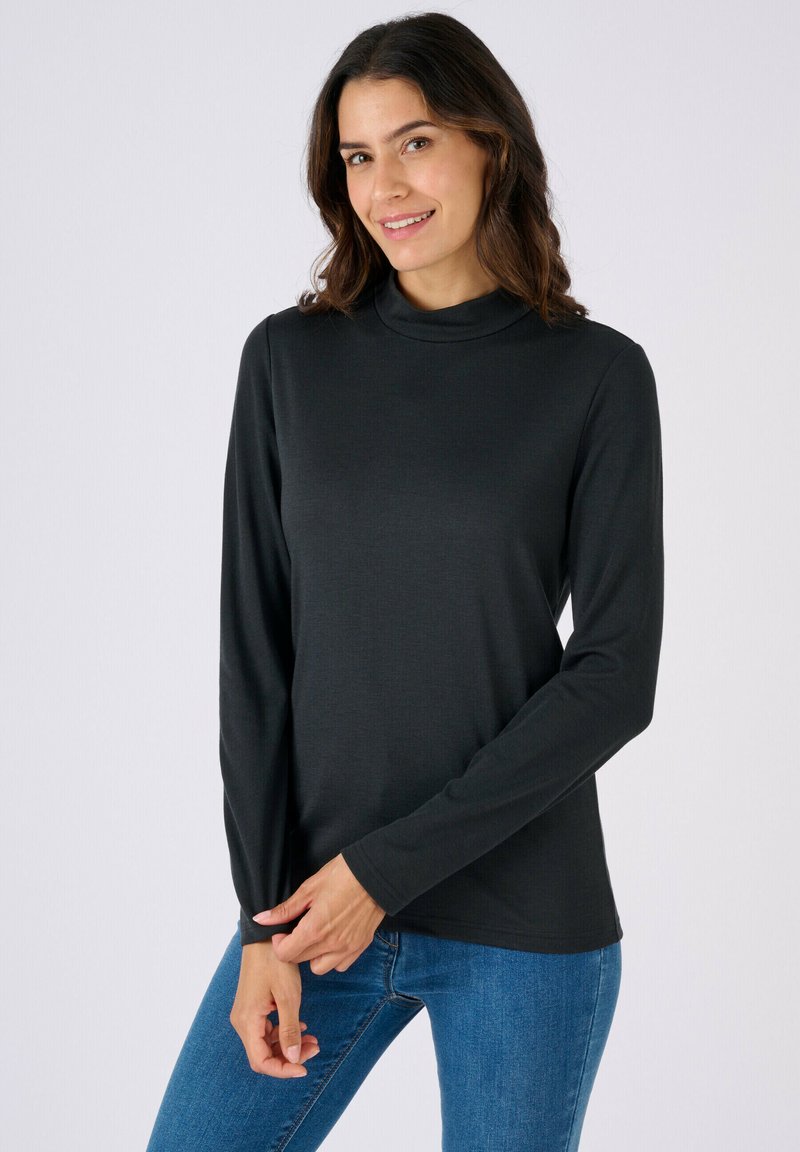 Haut noir à manches longues avec un col montant, confectionné dans un tissu doux et léger. Coupe ajustée aux manches et coupe décontractée à la taille.