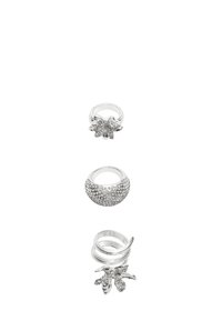 Sæt af fire sølvringe med forskellige designs: en med klare ædelsten, en glat ring og to med blade mønstre.