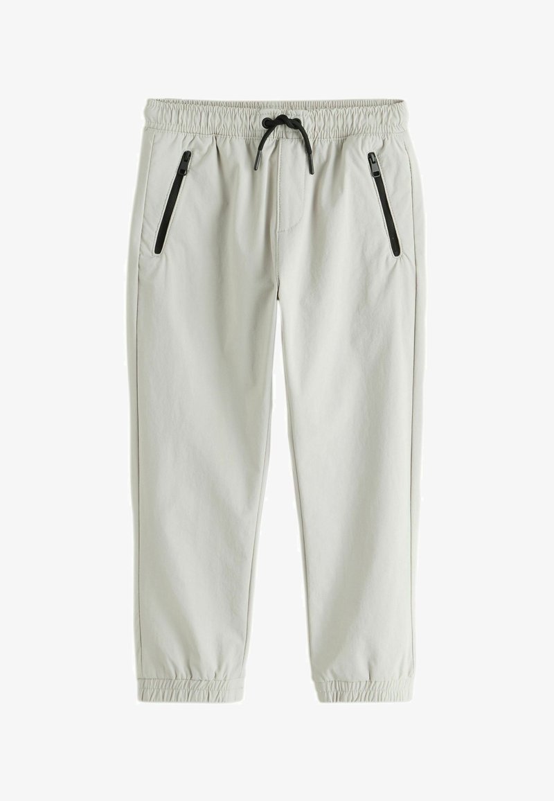 Pantalon de jogging gris clair avec taille et poignets élastiques, doté de poches latérales zippées noires et d'un cordon de serrage noir.