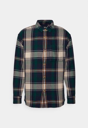 Chemise à carreaux en tissu épais, comprenant des couleurs marine, verte, beige et orange ; devant boutonné et manches longues avec poignets boutonnés.