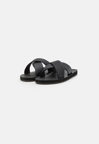 Svarta slidesandaler med ett texturerat vävt rem och en slät gummisula, designade för komfort och vardagligt bruk.