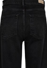 Vue arrière d'un jean en denim noir montrant deux poches arrière et un patch de marque en cuir marron sur la ceinture.