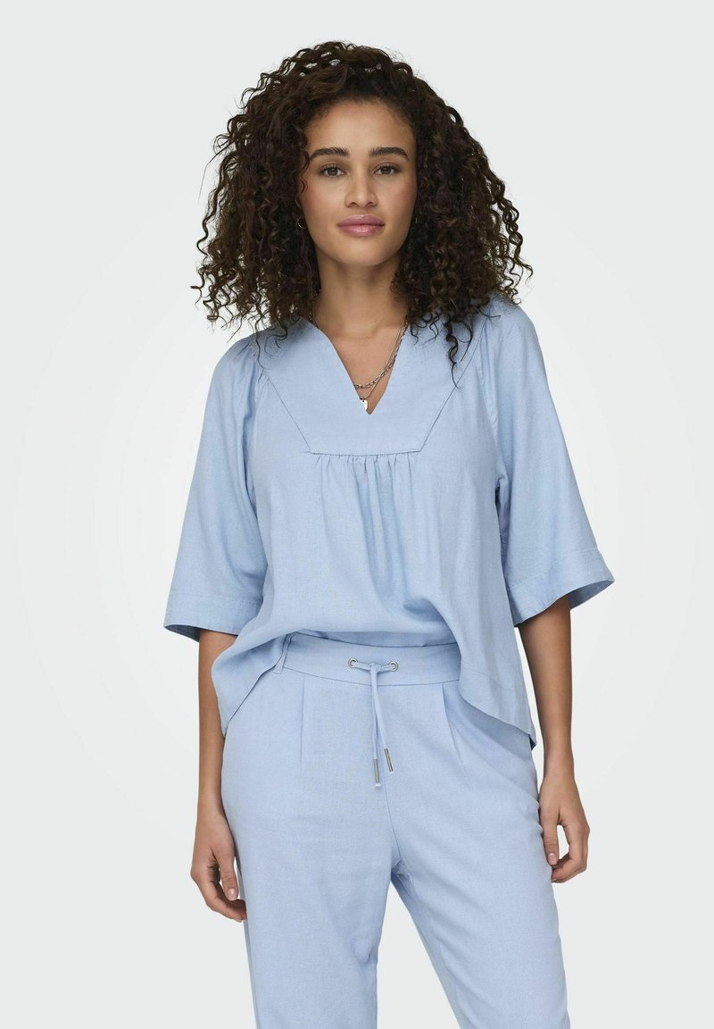 Maglietta azzurro chiaro, in fit rilassato, con maniche corte e scollatura a V, abbinata a pantaloni coordinati con coulisse per la vita regolabile.