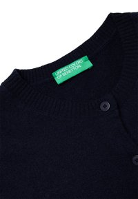 Dunkelblauer Cardigan mit rundem Ausschnitt, geripptem Saum und zwei schwarzen Knöpfen; verfügt über ein grünes Etikett mit der Aufschrift "UNITED COLORS OF BENETTON."