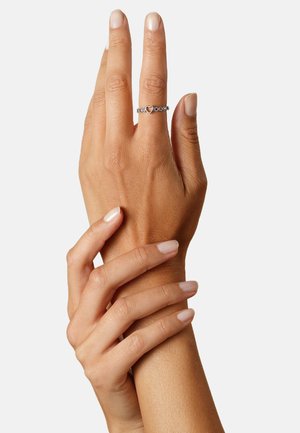 Zilveren ring met hartvormig ontwerp, geaccentueerd met kleine steentjes, gedragen aan de wijsvinger. Twee handen verstrengeld, met zichtbare verzorgde nagels.