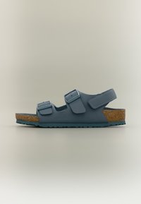 Μπλε σανδάλι με δύο ρυθμιζόμενες αγκράφες και ένα λουράκι με βέλκρο, πάτο από φελλό και υφή στην σόλα, απεικονιζόμενο σε πλαϊνή όψη σε ουδέτερο φόντο.