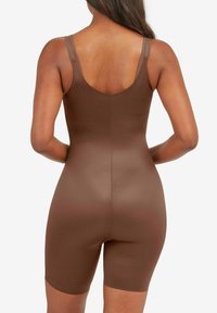 Pruun bodysuit, millel on sulanduv disain, õlalintidega ja ümar seljaosa. Materjal näib olevat sile ja veniv, ulatudes kuni reiele.