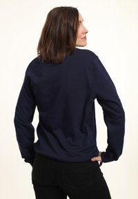 Felpa a maniche lunghe blu navy in tessuto morbido, con collo rotondo e polsini a costine. Design semplice senza motivi o grafiche visibili.