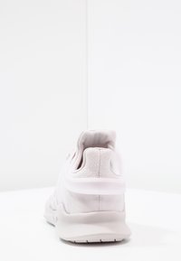 Ljust rosa sneaker med en texturerad mesh-övre, vadderad krage och en gummisula. Har en genomskinlig häl och minimalistic design.