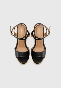 Black leather sandals with a wide front strap and a back ankle strap. Soft interior and textured sole. Brand name embossed on the footbed.